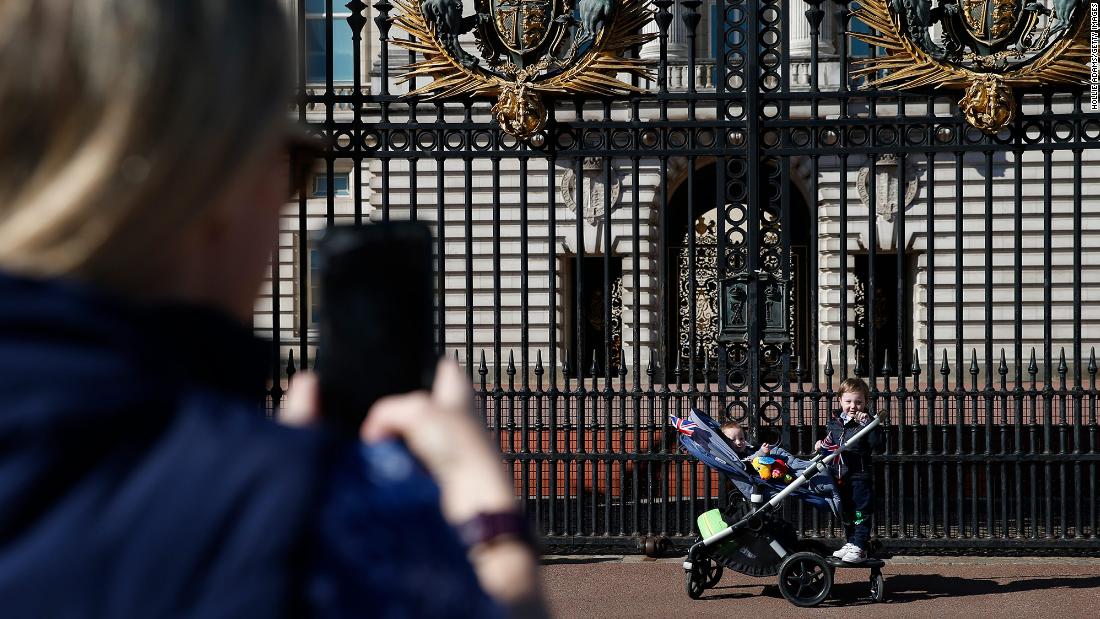 A woman takes a photo of her children outside Buckingham Palace on Saturday.