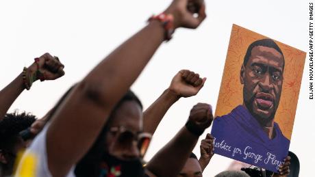 People raise their fists and hold a portrait of George Floyd during a rally following the guilty verdict the trial of Derek Chauvin on April 20, 2021, in Atlanta, Georgia. (Photo by ELIJAH NOUVELAGE/AFP via Getty Images)