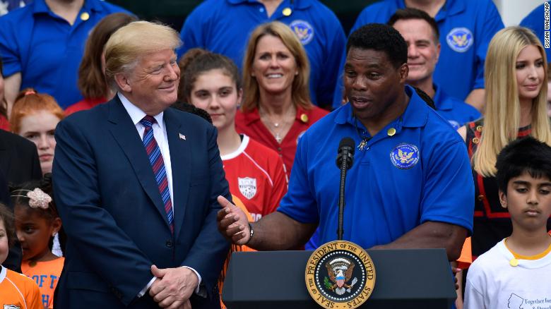 Then-President Donald Trump listens as Herschel Walker speaks on the South Lawn of the White House in May 2018.