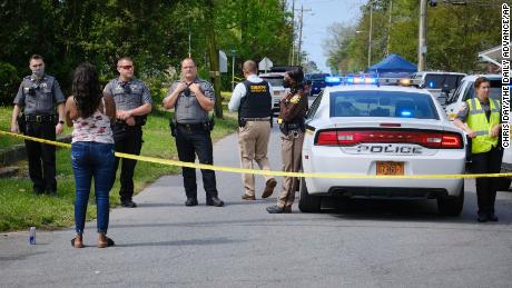 Law enforcement officers watch as a woman records the scene on her cell phone.