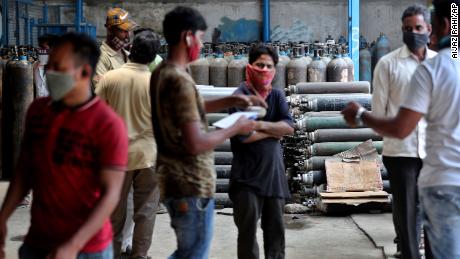 Ambulance drivers and others wait to receive oxygen cylinders at a gas supplier facility in Bengaluru, India, on April 21.