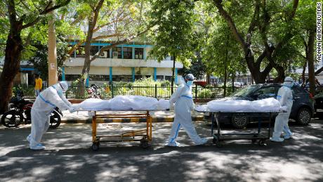 Des agents de santé portant des équipements de protection individuelle transportent les corps de personnes atteintes de Covid-19 devant l'hôpital Guru Teg Bahadur, à New Delhi, en Inde, le 24 avril.