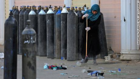 An Iraqi woman sweeps up debris Sunday next to oxygen bottles brought outside the Ibn Al-Khatib Hospital in Baghdad following Saturday night&#39;s fire.