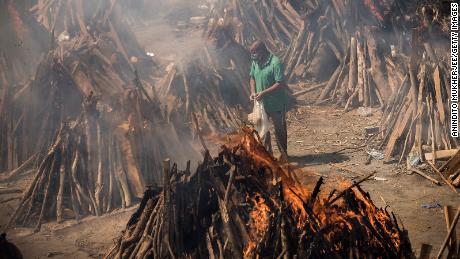 A man performs the last rites of a relative who died of Covid-19, as other funeral pyres are seen burning during a mass cremation in New Delhi, India, on April 24.