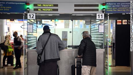 Travellers shows their documents to a border police officer at the immigration desk of Roissy Charles-de-Gaulle international airport, on February 1, 2021, as new Covid-19 border restrictions come into effect. - All but essential travel from outside the EU has been banned in France, while testing requirements on travellers from within the EU has been tightened. (Photo by Christophe ARCHAMBAULT / AFP) (Photo by CHRISTOPHE ARCHAMBAULT/AFP via Getty Images)