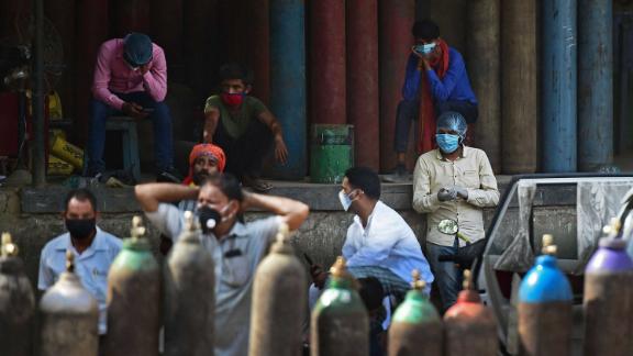 People wait to refill their oxygen cylinders at a refilling station in Allahabad on April 24.