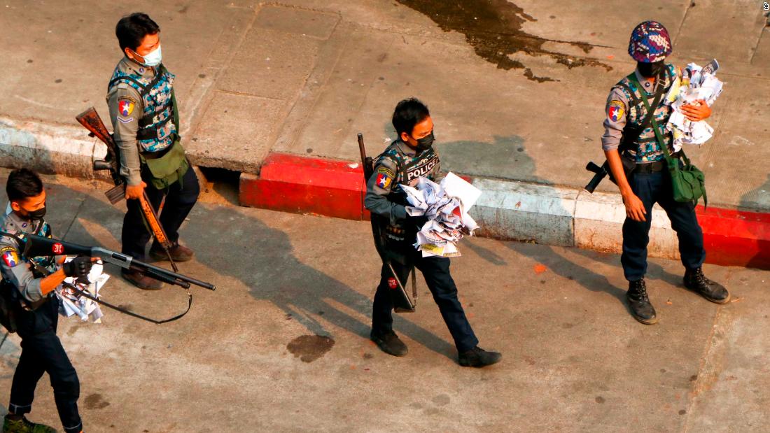 Police officers clear a road after demonstrators spread placards in Yangon on Saturday, April 24.