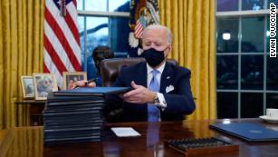 President Joe Biden signs his first executive orders in the Oval Office of the White House on Wednesday, Jan. 20, 2021, in Washington. 
