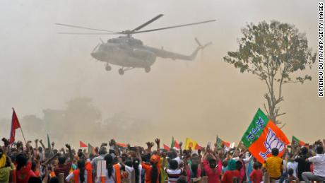Сторонники партии Моди Бхаратия Джаната (BJP) машут рукой в ​​сторону вертолета, в котором находится премьер-министр, когда он прибывает на митинг 10 апреля. 