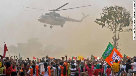 Supporters of Bharatiya Janata Party (BJP) wave towards a helicopter carrying Indian Prime Minister Narendra Modi upon his arrival at a public rally at Kawakhali on the outskirts of Siliguri on April 10, 2021. 