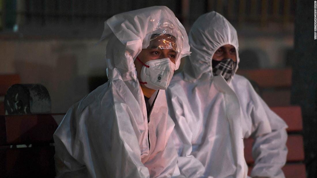 People wear protective suits while watching a relative&#39;s cremation in New Delhi on April 28. Their loved one died from Covid-19.