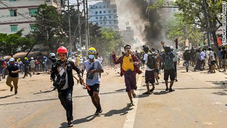 Protesters run as tear gas is fired during a crackdown by security forces on a demonstration against the military coup in Yangon&#39;s Thaketa township on March 19.