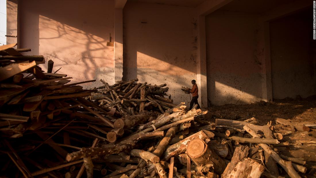 A worker at a mass crematorium carries logs of wood for funeral pyres as people perform the last rites for some Covid-19 victims in New Delhi on May 1.