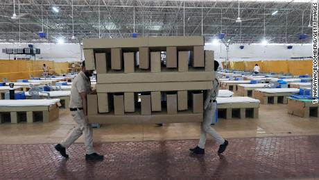 Workers carry biodegradable cardboard beds in a makeshift ward at the Sardar Patel Covid Care Centre and Hospital in New Delhi, India, on April 24, 2021. 