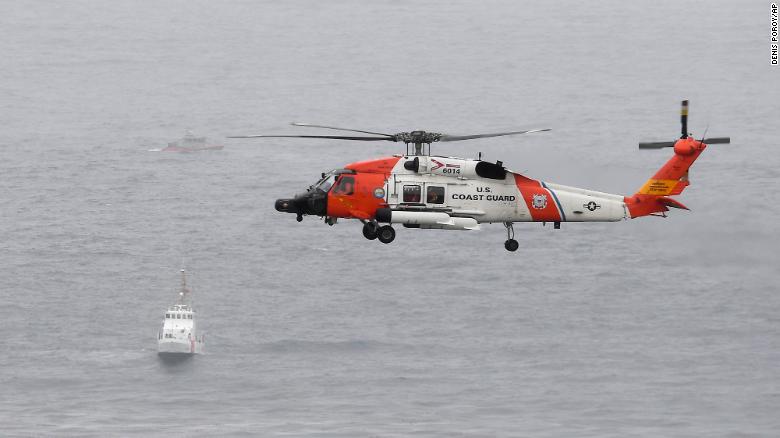 A US Coast Guard helicopter flies over boats searching the area where a vessel capsized off the San Diego coast Sunday.