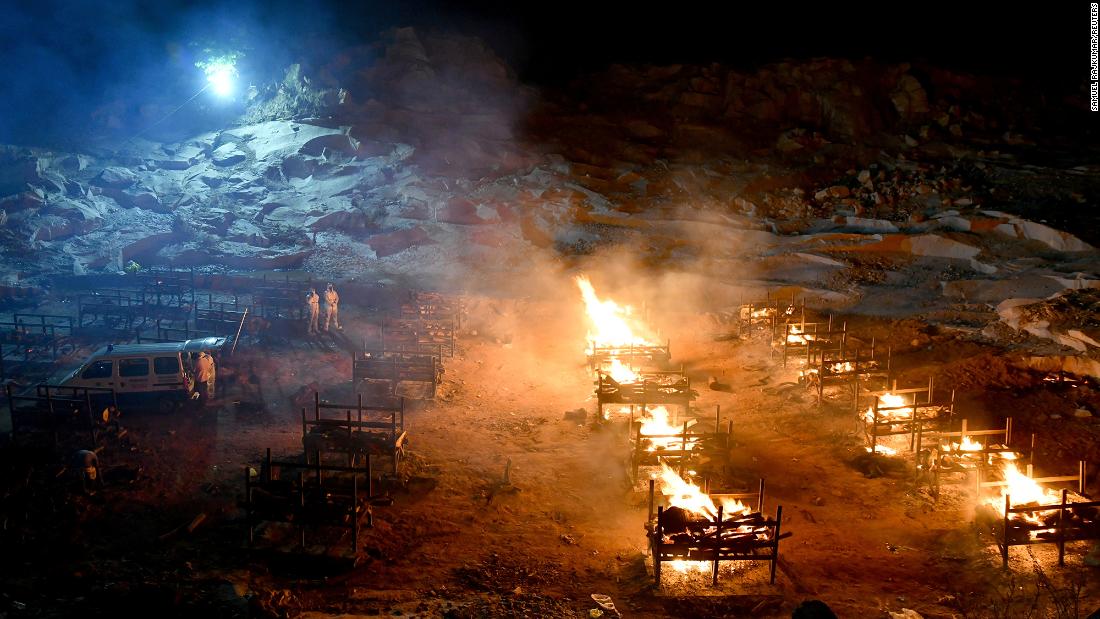 Volunteers stand next to burning pyres at a crematorium on the outskirts of Bengaluru on May 2.