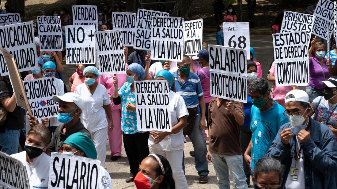 Health workers carry signs while participating in a protest outside a hospital in Caracas, Venezuela, on May 1. During the protest, which was part of International Workers&#39; Day, they demanded better wages and working conditions as well as mass vaccinations against Covid-19.