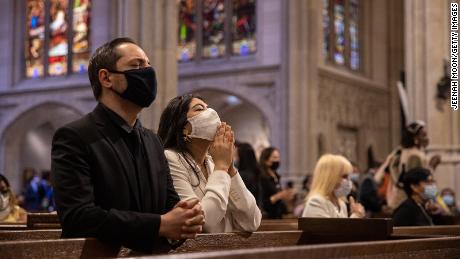 People wearing protective masks pray during a mass at Saint Patrick&#39;s Cathedral on April 4, 2021 in New York City. 