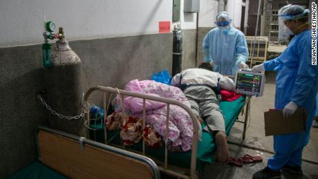 Nepalo gydytojai gegužės 5 dieną Katmandu (Nepalas) ligoninės greitosios pagalbos koridoriuje gydo pacientą COVID-19.