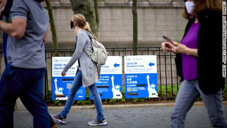 Pedestrians pass in front of Covid-19 vaccination site signs in New York on April 30.