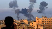 A Palestinian boy watches smoke billowing from buildings during Israeli airstrikes on the southern Gaza region of Khan Yunis, on May 11, 2021