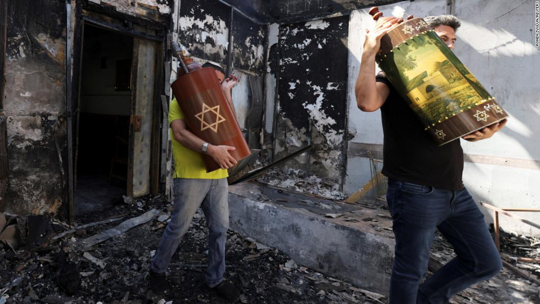 Torah scrolls, Jewish holy scriptures, are removed from a synagogue that was burned during confrontations between demonstrators and police in Lod, Israel, on May 12.