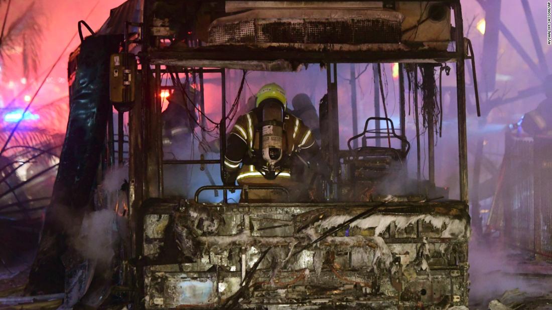 An Israeli firefighter extinguishes a burning bus in Holon, Israel, after it was hit by a rocket fired from Gaza on May 11.