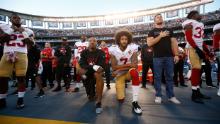 Eric Reid and Kaepernick kneel on the sideline during the national anthem.