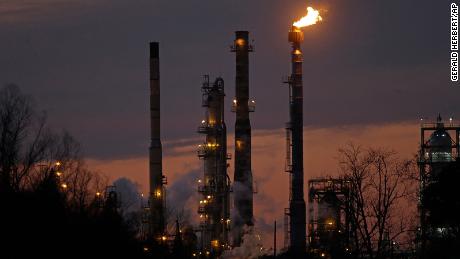 FILE - In this Feb. 13, 2015 file photo, stacks and burn-off from the ExxonMobil refinery are seen at dusk in St. Bernard Parish, La. New York City officials say they will begin the process of dumping about $5 billion in pension fund investments in fossil fuel companies, including Exxon Mobil, because of environmental concerns. (AP Photo/Gerald Herbert, File)