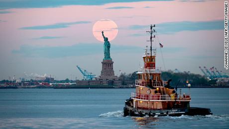 The lovely flower moon from 2020 looms over the Statue of Liberty in New York Harbor.