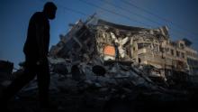 A Palestinian walks next to a building destroyed by Israeli airstrikes in Gaza City on Thursday, May 13.