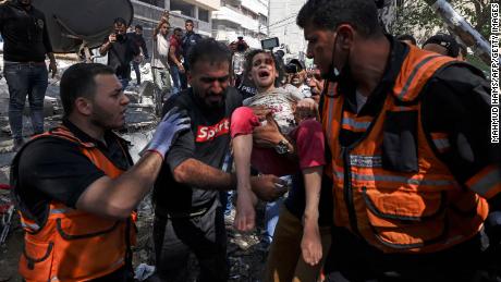 Palestinian paramedics evacuate a girl from the rubble of a building that was destroyed by an Israeli airstrike in Gaza&#39;s al-Rimal residential district on May 16.