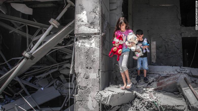 Children salvage toys from their home at Gaza City&#39;s Al-Jawhara Tower, which was heavily damaged in Israeli airstrikes.