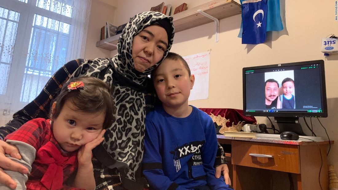 Amannisa Abdullah with daughter, Amina, 3, left, and son Musa, 8. Amina was born in Turkey and has never met her father, Ahmad Talip, pictured on screen in the background with Musa.