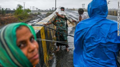 Os moradores tentam cruzar um cabo de alimentação que caiu em uma ponte perto de Dew, na Índia, em 18 de maio.