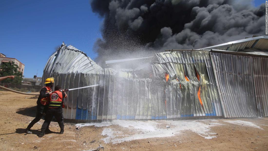 Firefighters work to extinguish a blaze at a warehouse in Rafah, Gaza, after it was hit by Israeli airstrike on May 18.