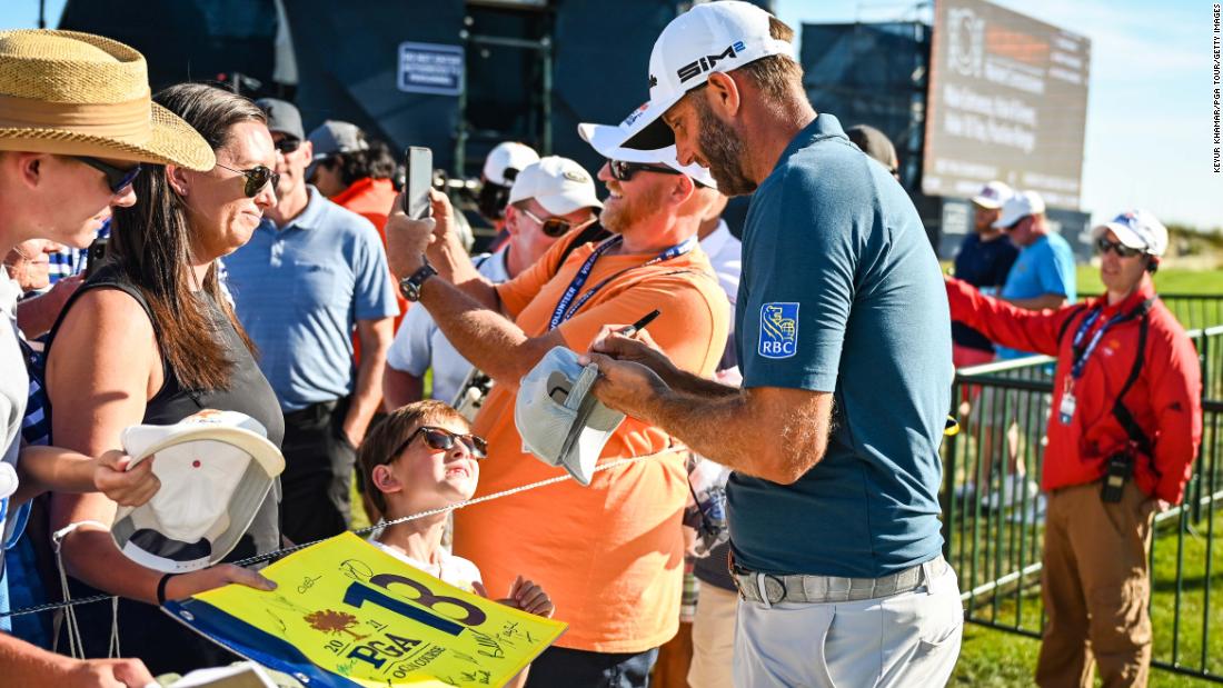 Dustin Johnson signs autographs for fans on the 18th hole during practice.