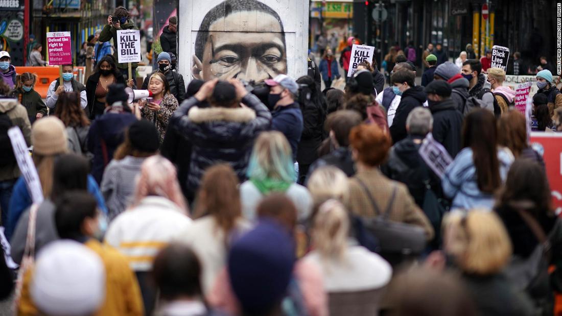 People kneel in front of a Floyd mural during a protest in Manchester, England, on March 27.