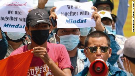 Protesters hold signs in support of the town of Mindat in Chin state, during a demonstration in Mandalay on May 17.
