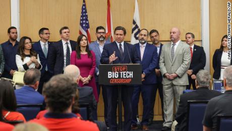 Florida Gov. Ron DeSantis, center, gives his opening remarks flanked by local state delegation members prior to signing legislation that seeks to punish social media platforms that remove conservative ideas from their sites, inside Florida International University&#39;s MARC building in Miami on Monday, May 24, 2021. (Carl Juste/Miami Herald via AP)