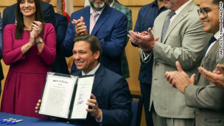 Florida Gov. Ron DeSantis hold up the signed legislation that seeks to punish social media platforms that remove conservative ideas from their sites, inside Florida International University's MARC building in Miami on Monday, May 24, 2021. (Carl Juste/Miami Herald via AP)
