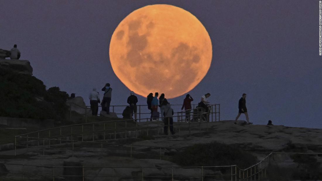People watch the moon rise over Sydney&#39;s Bondi Beach.