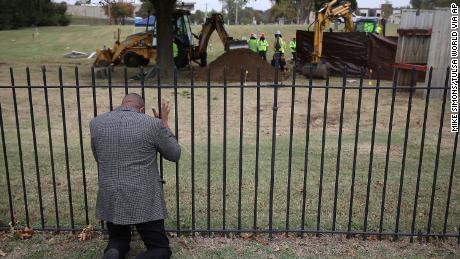 Rev. Robert Turner, with Vernon A.M.E Church, prays as crews work on a second test excavation and core sampling, Tuesday, Oct. 20, 2020, in the search for remains at Oaklawn Cemetery in Tulsa, Okla., from the 1921 Tulsa Race Massacre.