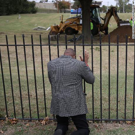 Rev. Robert Turner, with Vernon A.M.E Church, prays as crews work on a second test excavation and core sampling, Tuesday, Oct. 20, 2020, in the search for remains at Oaklawn Cemetery in Tulsa, Okla., from the 1921 Tulsa Race Massacre. (Mike Simons/Tulsa World via AP)
