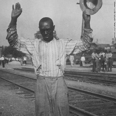 A man holding a hat with his hands up wearing suspenders surrenders during the Tulsa Race Massacre which occurred from May 31, 1921 through June 1, 1921 in Greenwood, Oklahoma. (Photo by Greenwood Cultural Center/Getty Images)