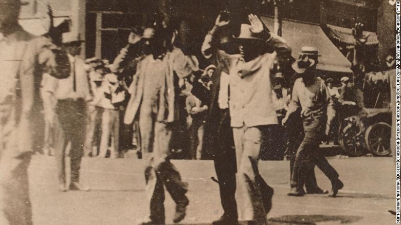 This photograph shows men walking with their hands raised during the Tulsa race massacre on June 1, 1921.