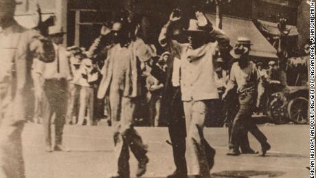 This photograph shows men marching with their hands raised during the Tulsa Race Massacre on June 1, 1921.
