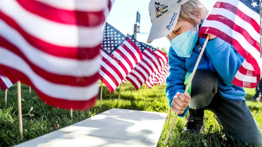 Elias Loosen plants a flag Saturday as part of the War Memorial Center&#39;s Field of Flags community event in Milwaukee.