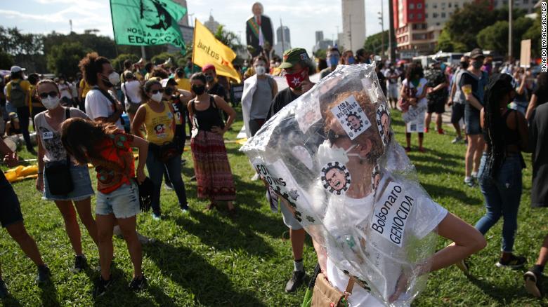 A protester wears a sign accusing Bolsonaro of genocide.