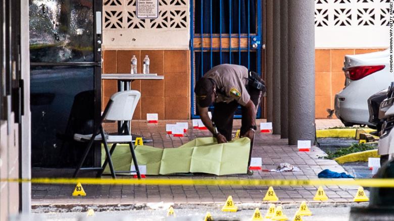 A Miami-Dade officer covers a body outside a club that was rented out for a concert.